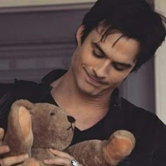 a man holding a brown teddy bear in his hands