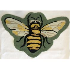 a yellow and black bee is on a white cloth with green border around the edges