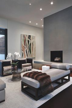 a living room with modern furniture and art on the wall behind the couches, along with a fireplace