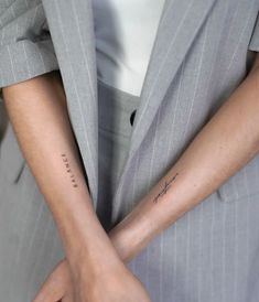 two people with matching tattoos on their arms, one holding the other's arm