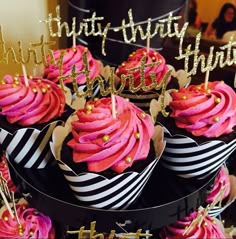 cupcakes with pink frosting and gold sprinkles are on display