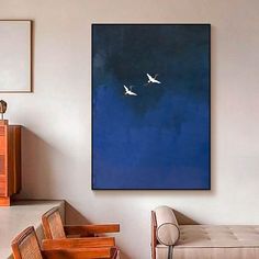 two birds are flying in the blue sky above a couch and table with chairs on it