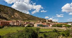 an old village nestled in the mountains under a blue sky with white clouds and green grass