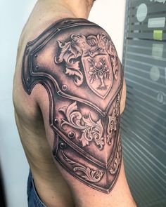 a man with a tattoo on his arm has a chest piece in the shape of a shield