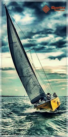 a yellow sailboat in the ocean under a cloudy sky