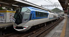 a blue and white train pulling into a station next to a platform with people on it