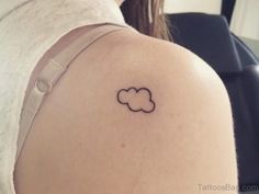 a small cloud tattoo on the back of a woman's left shoulder, it is black and white