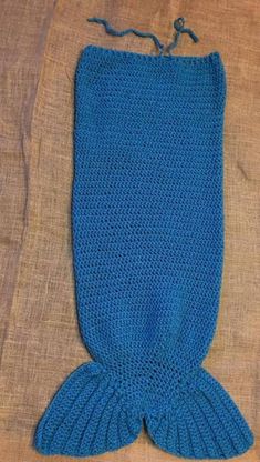 a blue knitted mermaid tail laying on top of a bed