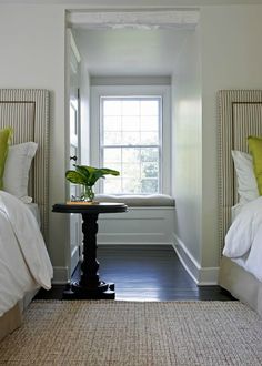 two beds with white sheets and yellow pillows in a room next to a small table