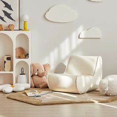 there is a white chair and teddy bear on the floor in front of a bookcase