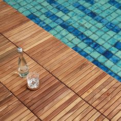 a bottle of water sitting on top of a wooden floor next to a swimming pool