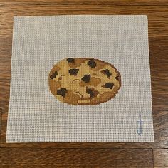 a cross - stitch picture of a cookie with chocolate chip cookies on it's surface