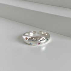 Journey into the vast expanse of the universe with our exquisite "Cosmic Arc" star ring. Fashioned from 925 Sterling Silver, this statement ring exemplifies the harmonious blend of a minimalist and chunky ring, capturing the sublime contours of a celestial curve in its unique semi-circular design. The arc proudly displays seven meticulously carved stars, with each one cradling a rainbow-hued zirconia, making it appear as though a fragment of the galaxy is resting upon the wearer's finger. Sporti Celestial Style Silver Crystal Ring, Celestial Silver Crystal Promise Ring, Celestial Silver Crystal Ring, Celestial Silver Crystal Ring For Promise, Celestial Sterling Silver Midi Rings As Gift, Silver Rings For Women Unique, Silver Star-shaped Celestial Midi Rings, Silver Star-shaped Ring With Gemstone, Celestial Sterling Silver Star Ring