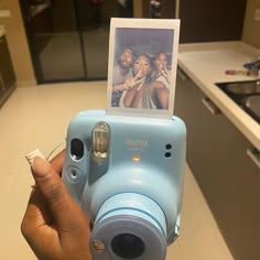 a person holding up a blue camera with a picture on the front and back of it