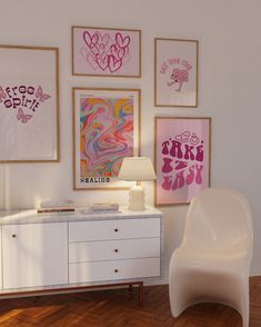 a white chair sitting next to a table in a room with pictures on the wall