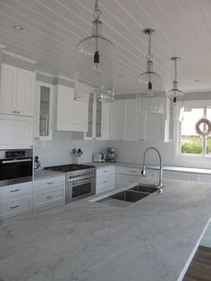 a kitchen with white cabinets and marble counter tops, an oven, sink and window