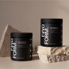 two black containers sitting next to each other on top of a white surface with rocks in the background