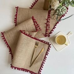 three placemats with red pompoms on them and a cup of coffee