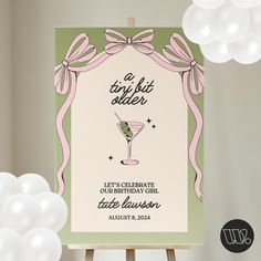 a birthday card with a martini glass and pink ribbon around it on an easel