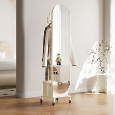 a mirror sitting on top of a wooden floor next to a white chair and table