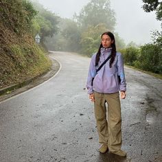 a woman standing in the middle of an empty road