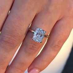 a woman's hand with a ring on it and a cushion shaped diamond in the middle