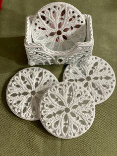 four white doily coasters sitting on top of a table