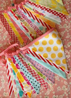 many different colored paper flags on a pink table cloth with white polka dots and stripes