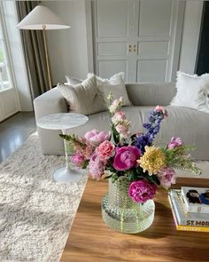 a vase filled with flowers sitting on top of a wooden table next to a white couch