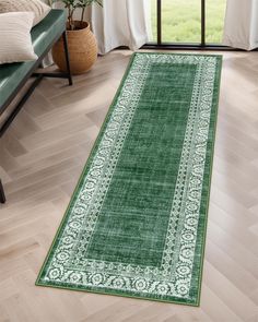 a green area rug on the floor in front of a window with white drapes