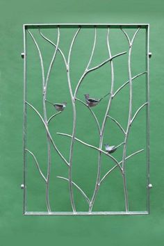 a metal screen with birds sitting on branches in front of a green wall and window