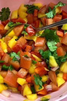 a pink bowl filled with chopped vegetables and garnished with cilantro leaves