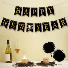 a happy new year banner with candles and wine glasses on a table next to it