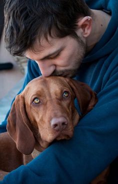 a man hugging his dog on the couch