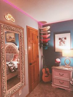 a bedroom with a bed, dresser and guitar on the wall in front of it