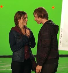 two people standing next to each other in front of a green screen with one person laughing