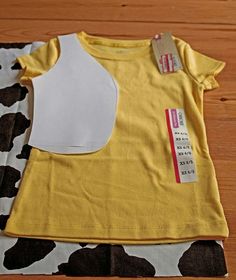 two yellow and white t - shirts sitting on top of a cow print table cloth