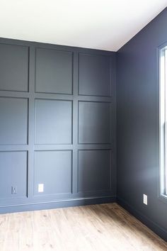 an empty room with wood flooring and dark gray paint on the wall behind it