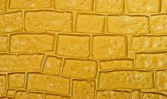 the texture of an alligator skin pattern is yellow and has drops of water on it