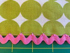 the pink thread has been stitched into the green and white fabric with yellow circles on it