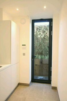 an empty room with a black door and white cupboards on either side of it