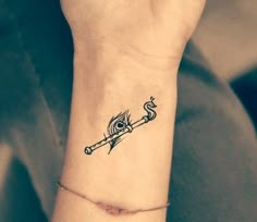 a woman's wrist tattoo with an arrow and eye on the left side of her arm