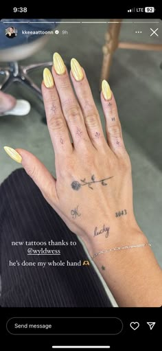 a woman's hand with yellow nails and tattoos