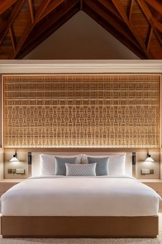 a large bed sitting under a wooden ceiling next to two wall mounted sconces