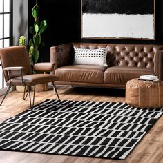 a brown leather couch sitting on top of a wooden floor next to a chair and ottoman