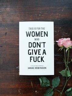 a book sitting on top of a wooden table next to a pink rose with the title, this is for the women who don't give a f