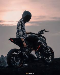 a man sitting on top of a motorcycle next to the ocean at sunset or dawn