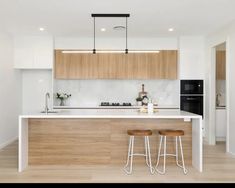 a kitchen with two stools next to an island