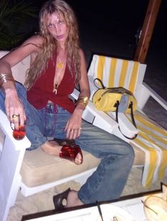 a woman sitting on a beach chair with her handbag and bottle in her other hand