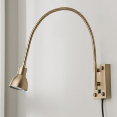 a light that is on the side of a white wall next to a black cord